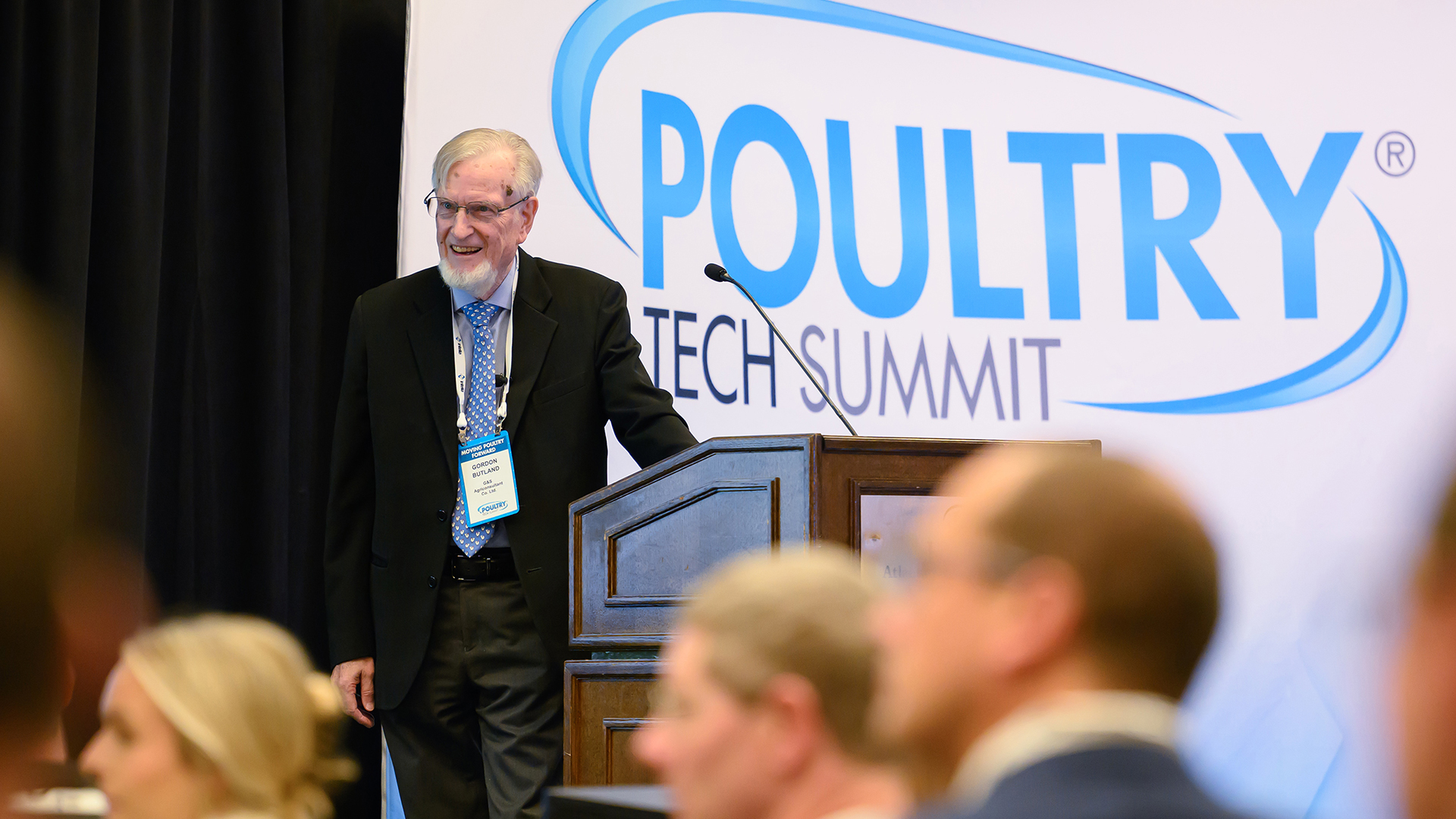 Poultry-Tech-Summit-speaker White man smiling on stage in front of audience